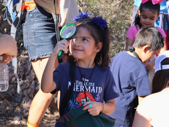 little girl looking through magnifying glass