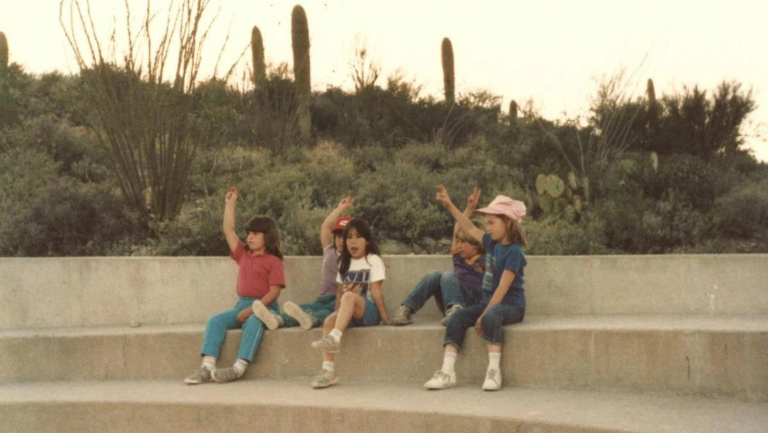 kids sitting in amphitheater setting with desert background