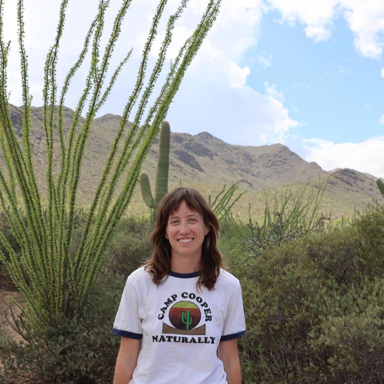 Brittne standing outside on a sunny day in a desert landscape 